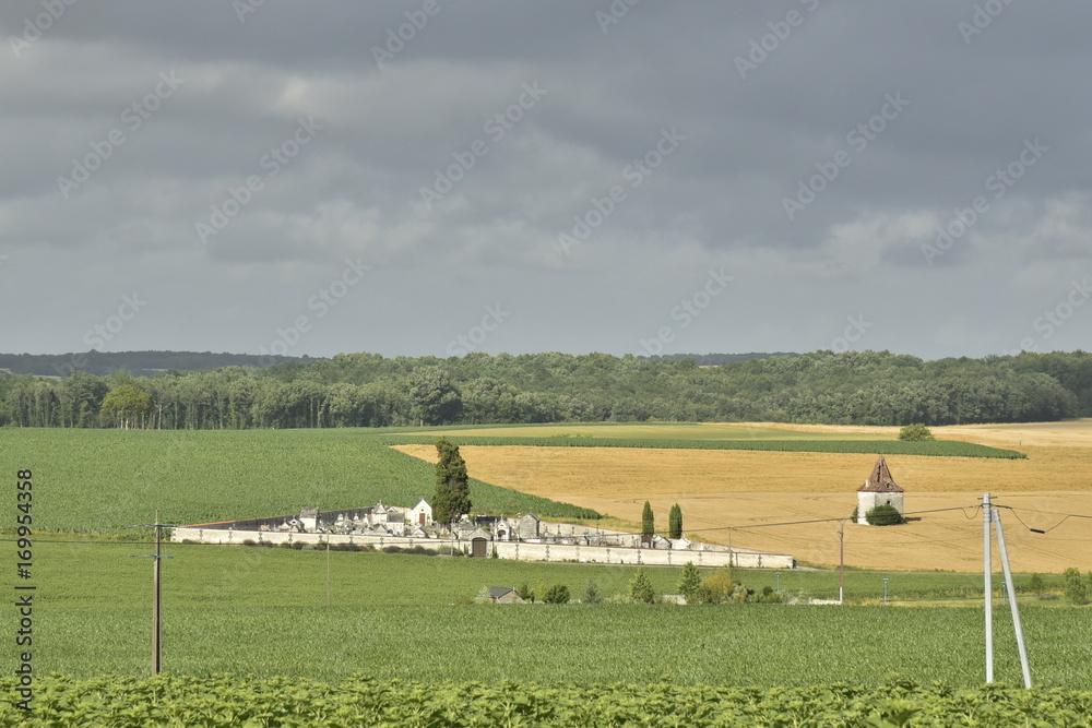 Cimetière rustique et pigeonnier en ruine au milieu des champs devant les nuages sombres d'orage ,au Périgord Vert Cimetière rustique et pigeonnier en ruine au milieu des champs devant les nuages sombres d'orage ,au Périgord Vert