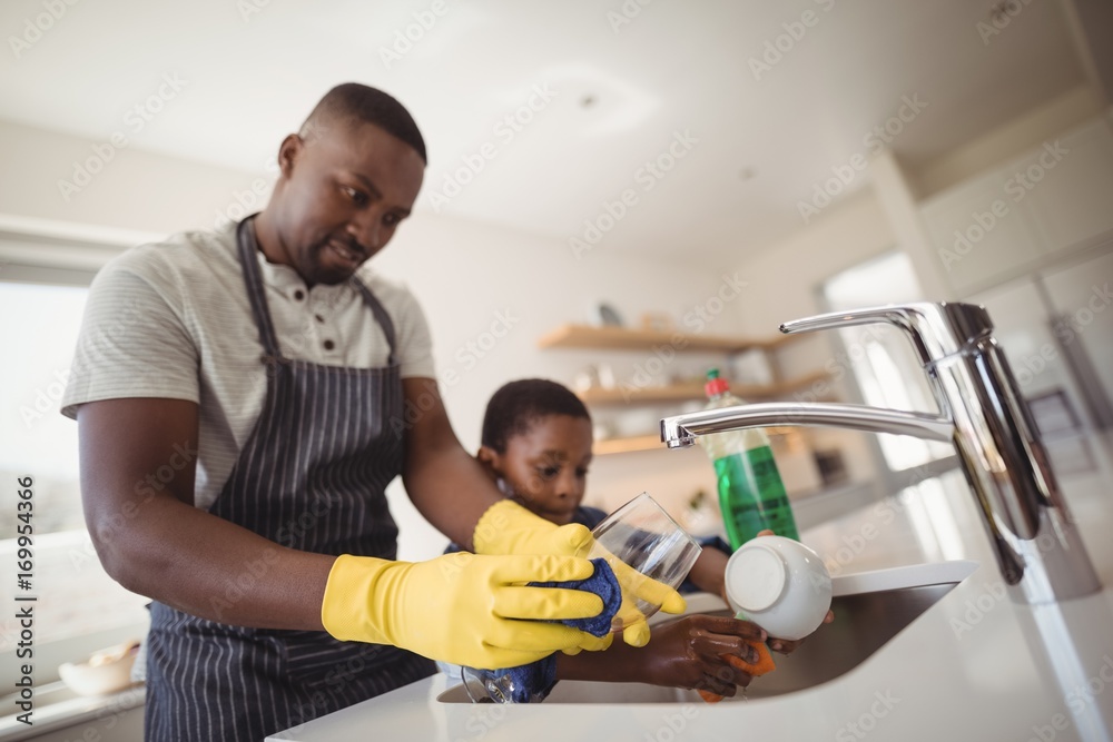 Father and son cleaning utensils in kitchen Father and son cleaning utensils in kitchen