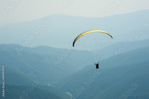 A paraglider fly over a mountain valley on a sunny summer day. Paragliding in the Carpathians in the summer.
