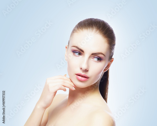Portrait of young, beautiful and healthy woman: over blue background. Healthcare, spa, makeup and face lifting concept.