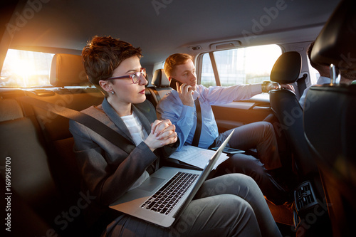 successful business people working together in back seat of car. © luckybusiness