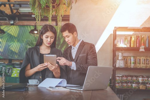 Two successful businessman Stand at the table and discussing business at the a laptop in a coffee shop. Businessmen dressed in formal wear