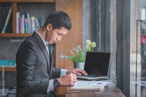 Young handsome man sitting in cafe with a cup of coffee Working at laptop and having a little break with copy space