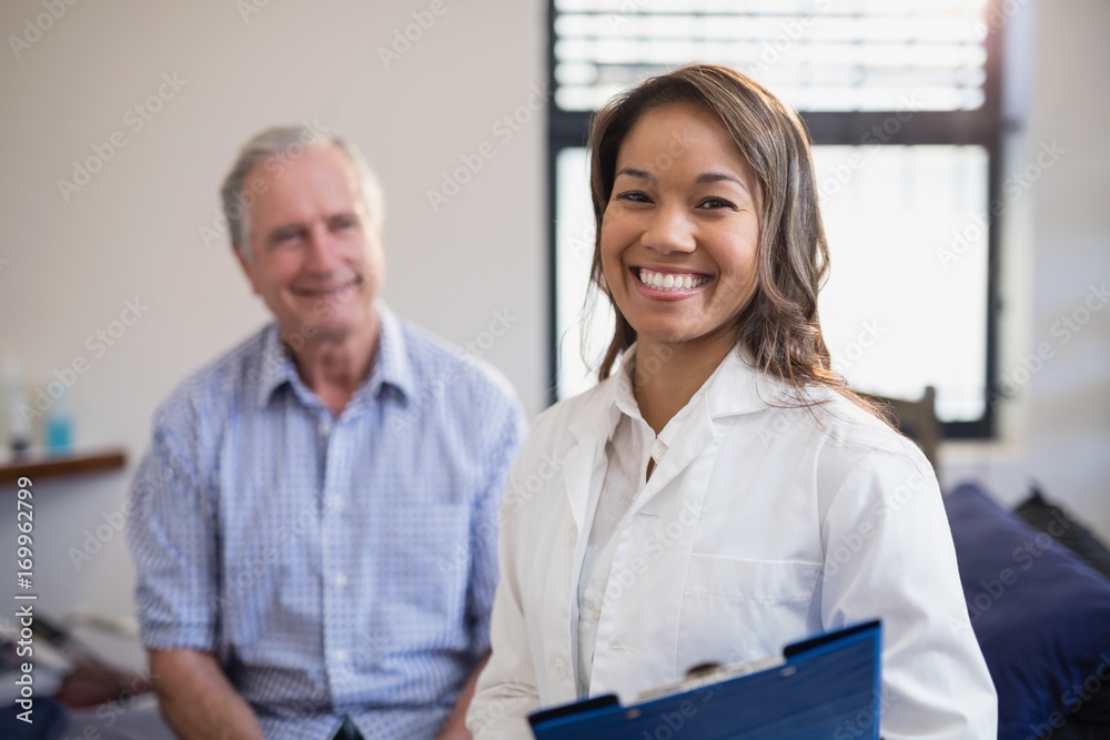 Fototapeta premium Portrait of smiling female therapist holding file with senior