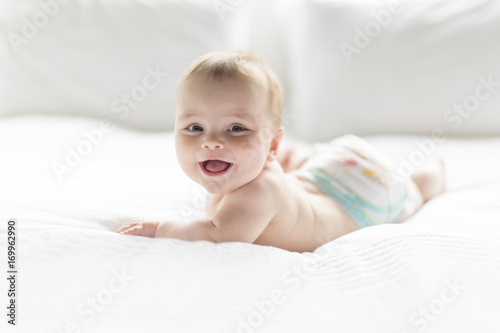 Photographie Cute happy 7 month baby girl in diaper lying and playing