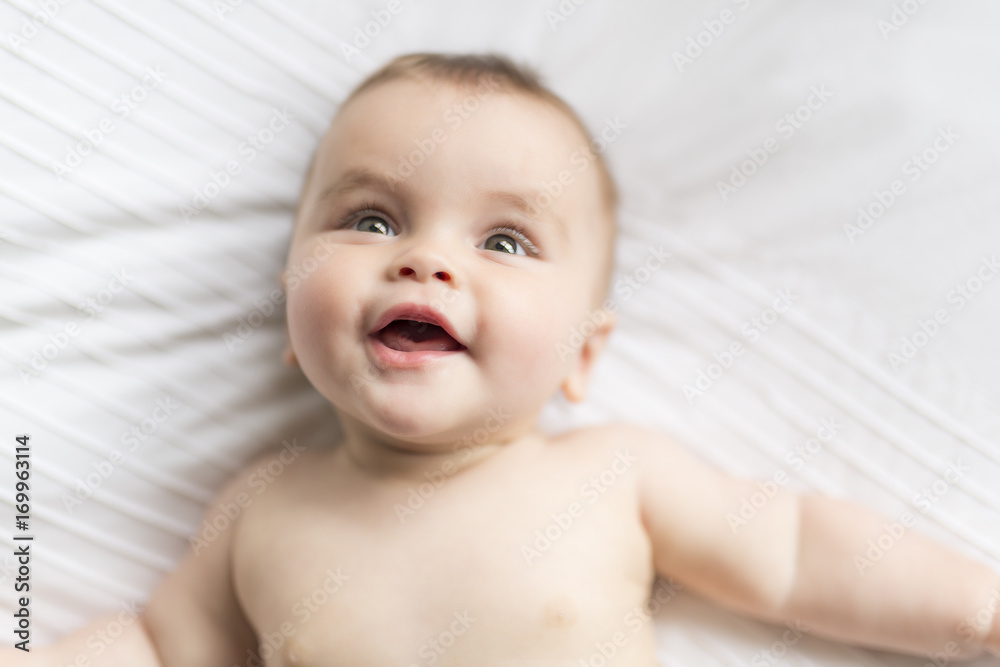 Cute happy 7 month baby girl in diaper lying and playing Cute happy 7 month baby girl in diaper lying and playing
