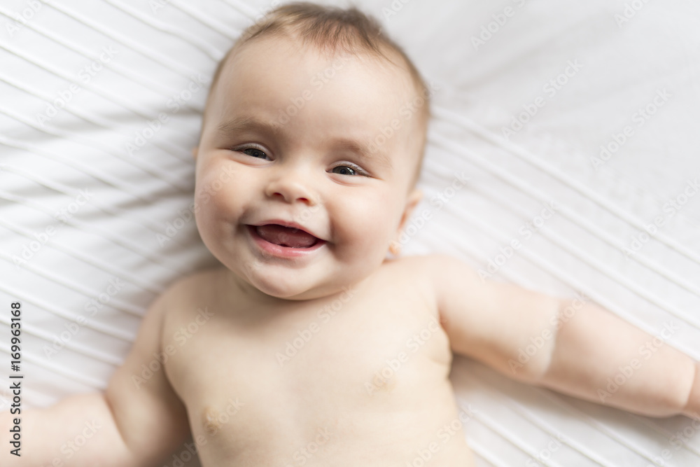 Cute happy 7 month baby girl in diaper lying and playing Cute happy 7 month baby girl in diaper lying and playing