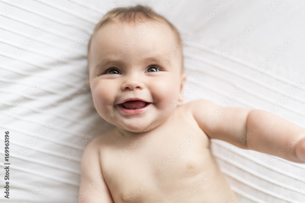 Cute happy 7 month baby girl in diaper lying and playing Cute happy 7 month baby girl in diaper lying and playing