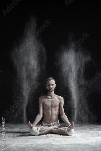 Sporty serene young man meditating sitting in cross-legged yoga lotus pose, Padmasana with palms in mudra © Viktor Koldunov
