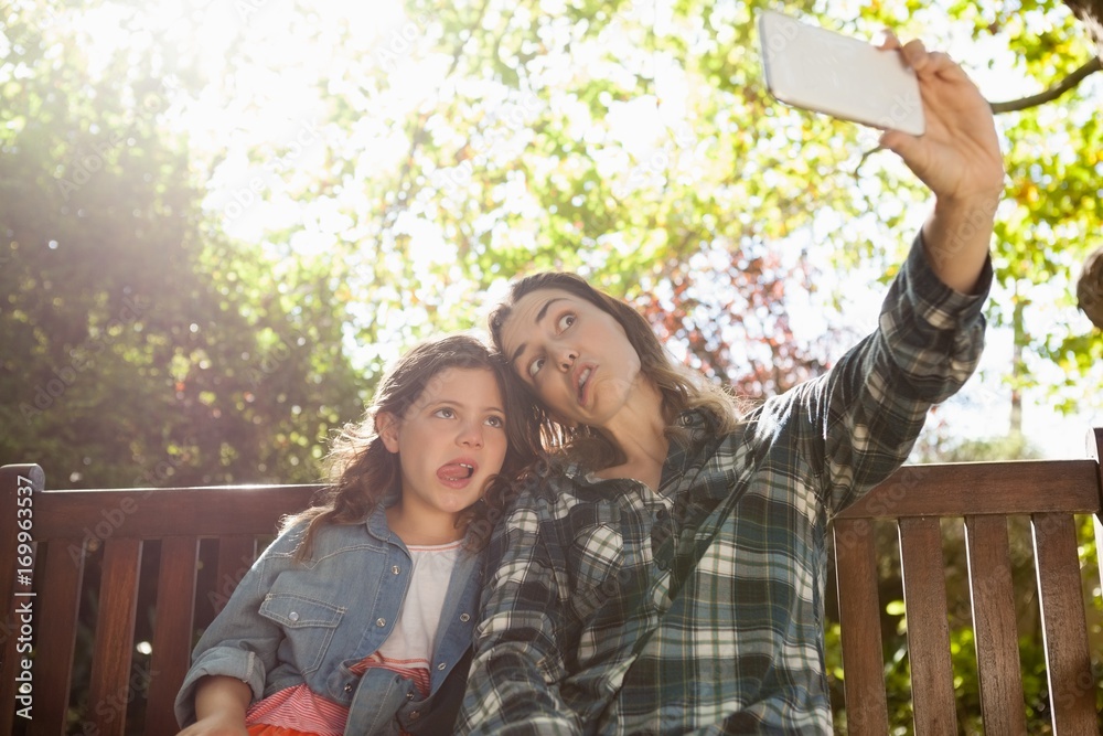 Naklejka premium Low angle view of woman taking selfie with daughter while making