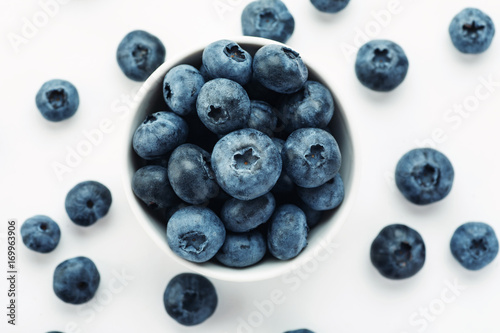 Heap of fresh ripe blueberries in a white ceramic bowl on a white background
