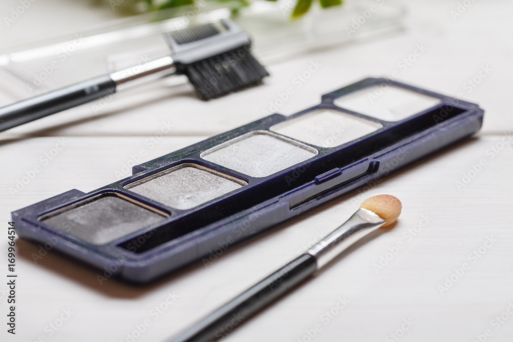 Cosmetic eyeshadow palette with brush on a white wooden table closeup shot Cosmetic eyeshadow palette with brush on a white wooden table closeup shot