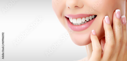 Closeup shot of woman's toothy smile against a grey background with copyspace