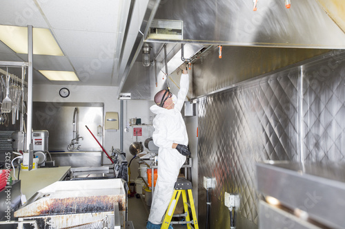 Commercial kitchen worker washing up at sink in professional kitchen photo