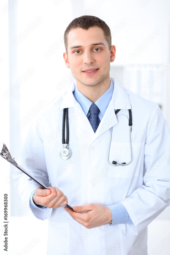 Smiling doctor waiting for his team while standing upright Smiling doctor waiting for his team while standing upright