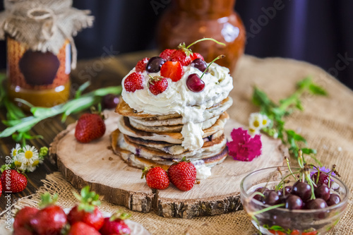 Delicious pancakes with berries on the authentic wooden stand. Summer food  pancakes sprinkled with cream and berries