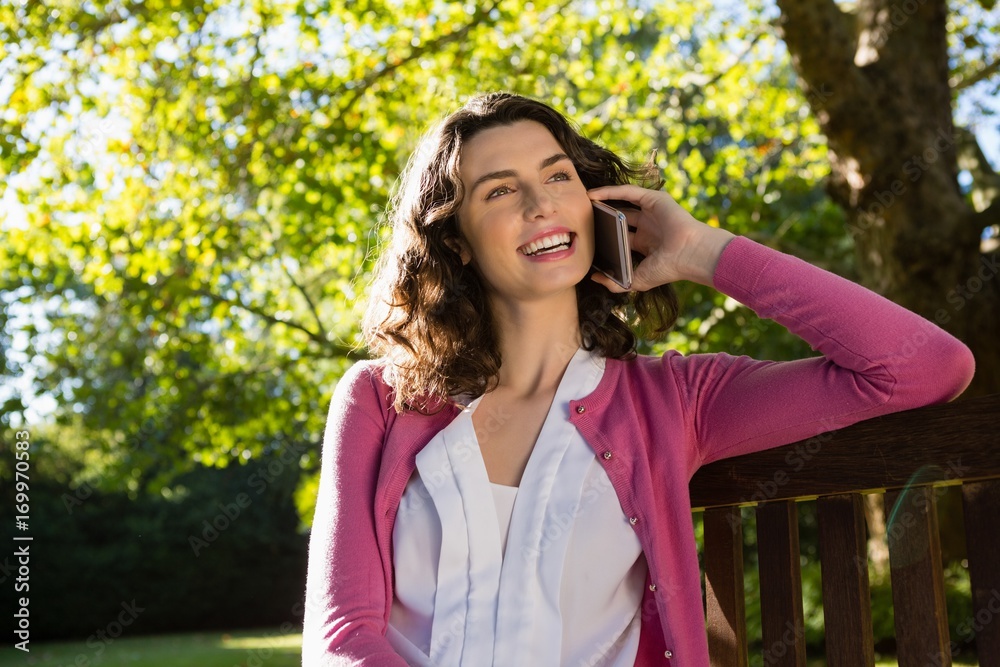Woman sitting on bench and talking on mobile phone Woman sitting on bench and talking on mobile phone