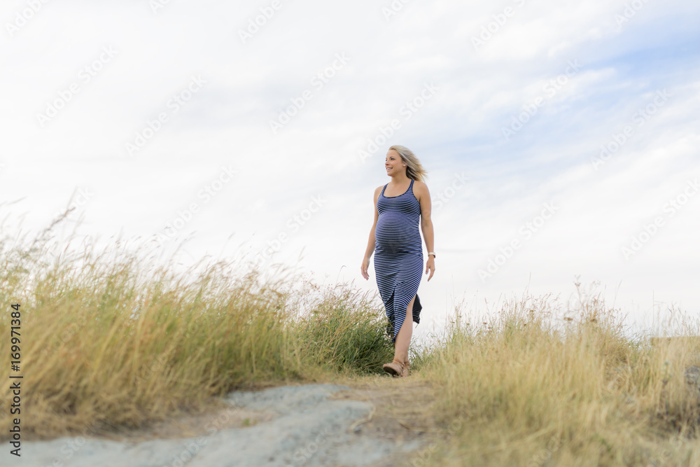 Portrait of a young beautiful blond pregnant woman on the side of the beach Portrait of a young beautiful blond pregnant woman on the side of the beach