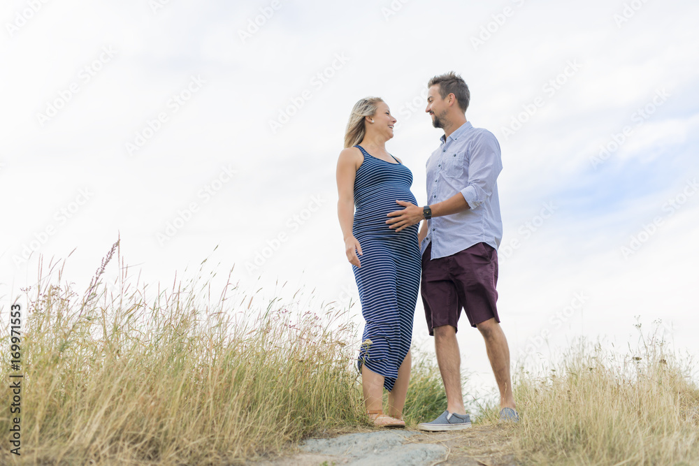 pregnant woman at beach with husband having fun pregnant woman at beach with husband having fun