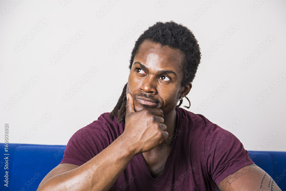 Obraz premium Handsome unsure, doubtful black man thinking, looking up with dubious expression on his face