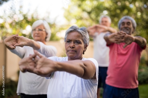 Senior friends stretching arms while exercising