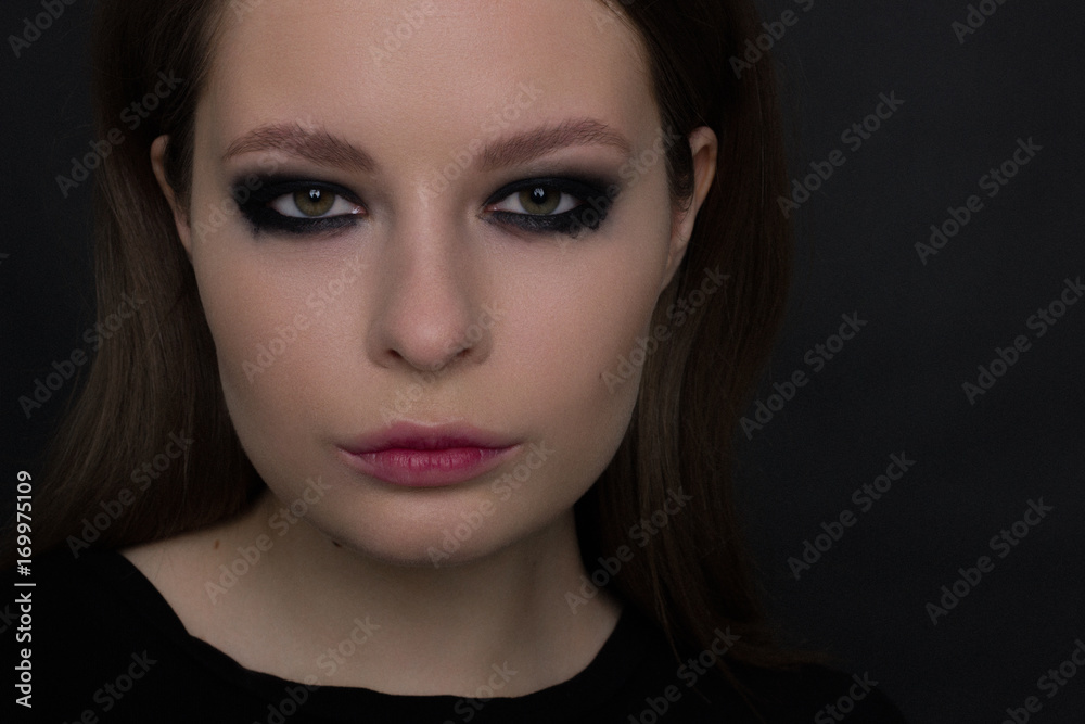 The beautiful woman with a languishing look and brown eyes. Gothic style, gloomy fashionable image. Smooth opaque skin, smoky eyes and natural lips The beautiful woman with a languishing look and brown eyes. Gothic style, gloomy fashionable image. Smooth opaque skin, smoky eyes and natural lips