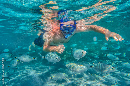 Young man snorkeling in underwater coral reef on tropical island