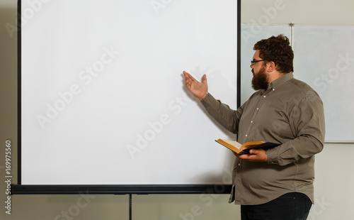 Fat young man with glasses holding a bookon white background photo