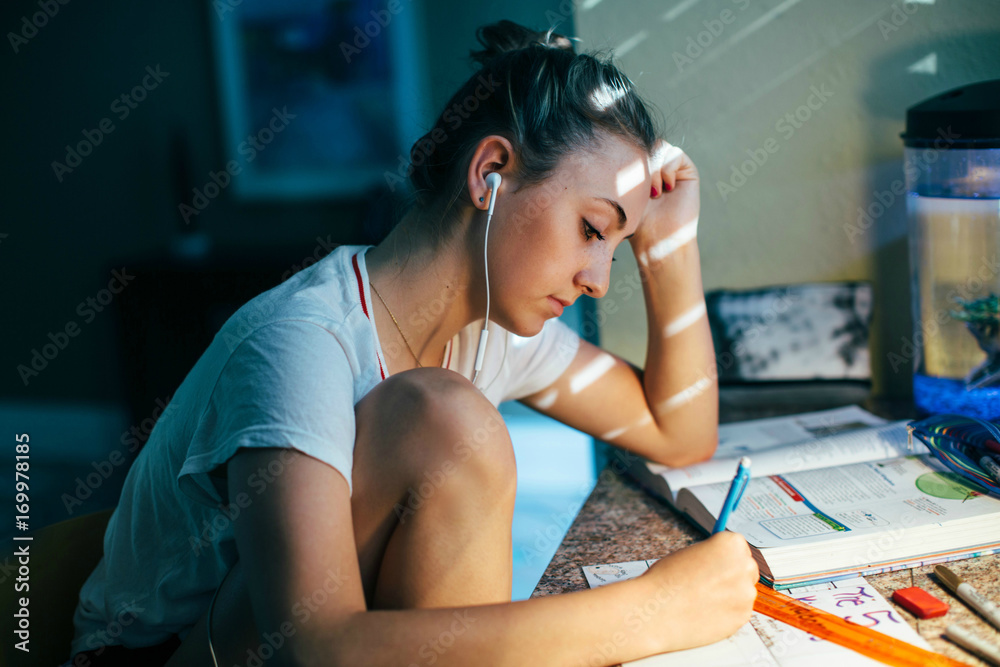 Profile of a teenage girl sitting at a desk doing homework Stock Photo ...