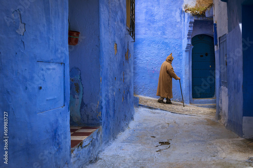 Chefchaouen, Morocco - April 10, 2016: Moroccan man walking in a narrow street in the town of Chefchaouen in Morocco, North Africa