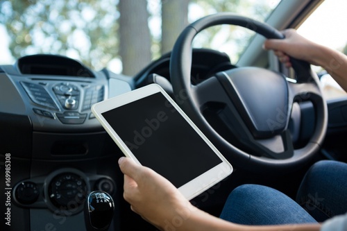 Woman using digital tablet while driving a car