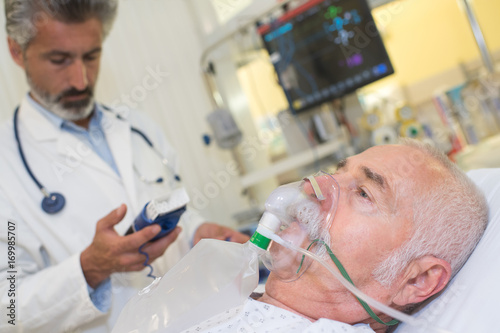 doctor near patient wearing oxygen mask in hospital room