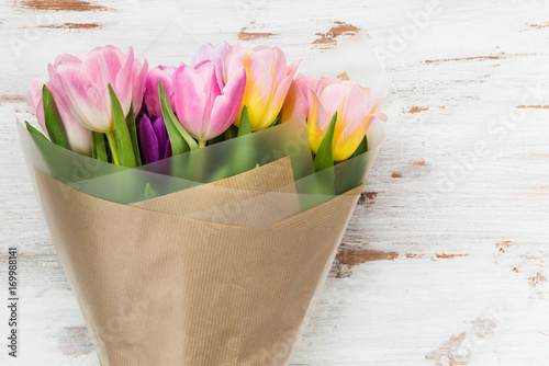 Tulips wrapped on brown paper on light background