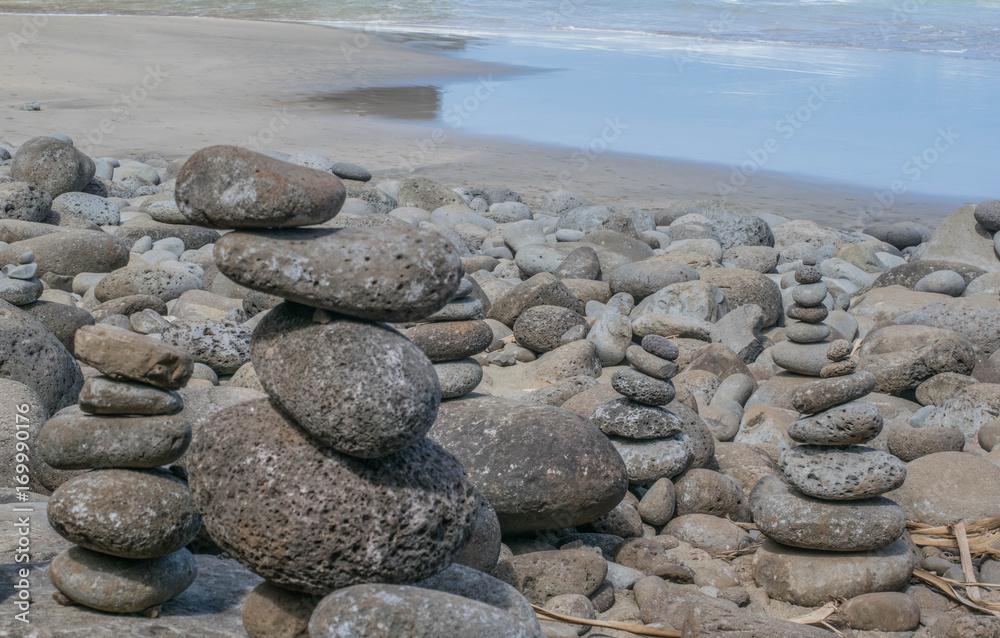 Naklejka premium Sandy beach, with several stacked stone figures in the foreground