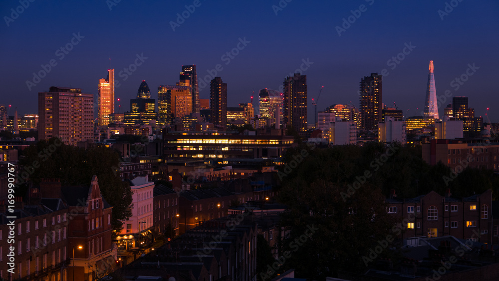 Night shot featuring the famous London skyline, including landmark buildings of the City of London, the financial powerhouse, contrasting with more traditional Victorian houses