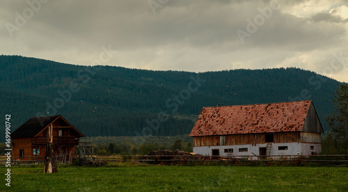 A wide angle shot of an abandoned log house located in a very remote rural village