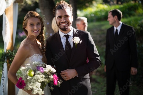 Happy bride and groom standing in park