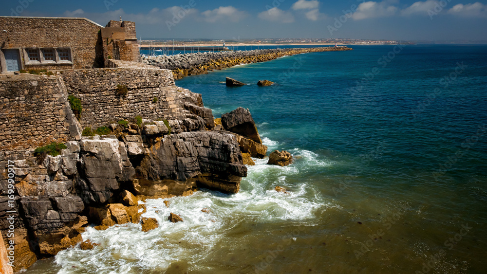 A panoramic shot featuring the sea, jetty and coast of the fishing village of Peniche, Portugal on a sunny day