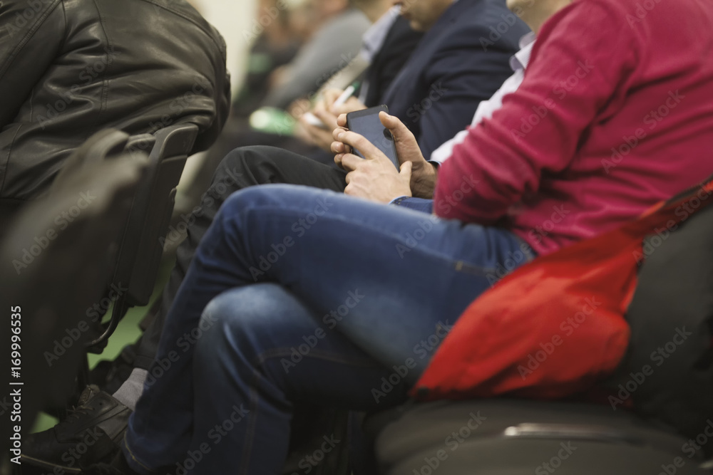 Man employee in suit uses digital device sitting on the forum about industry and economy