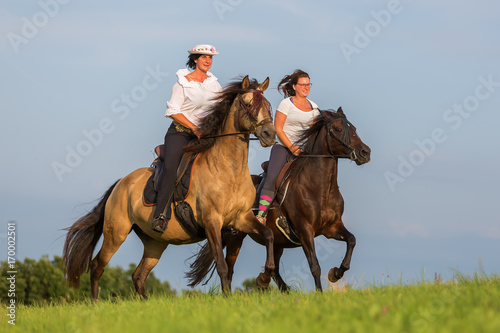 two women ride Andalusian horses