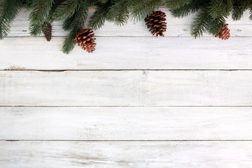 Christmas background - fir leaves and pine cones decorating rustic elements on white wood table. Creative Flat layout and top view composition with border and copy space design.