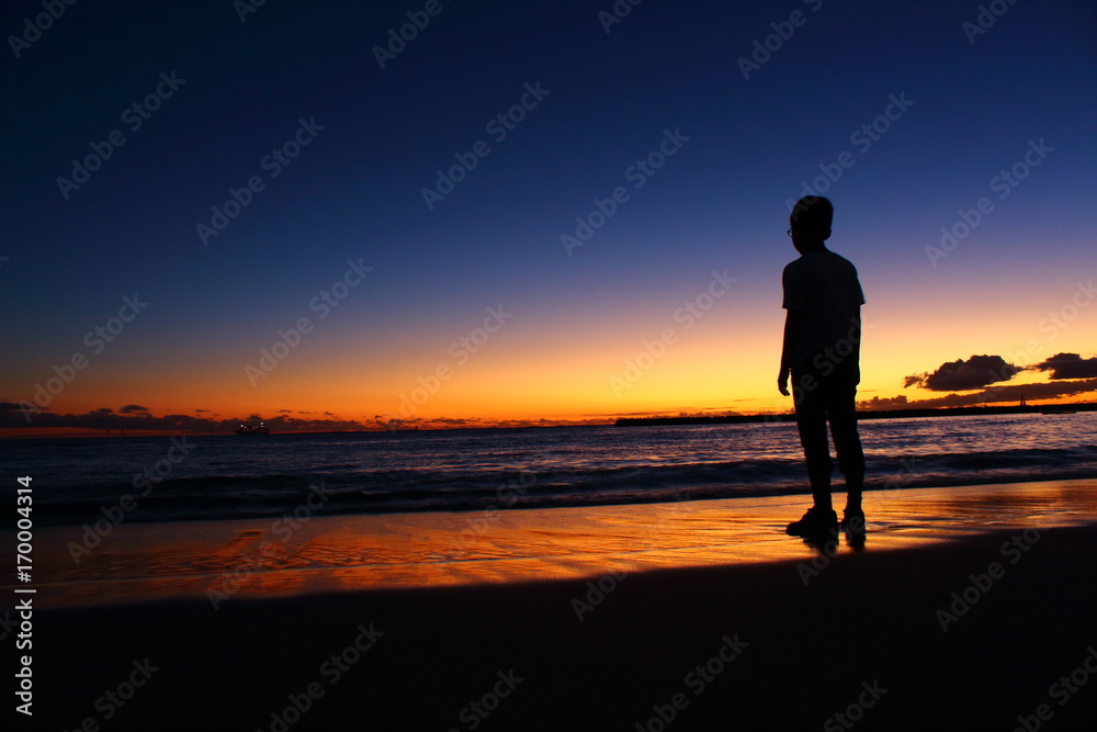 夕暮れの海辺に立つ子供のシルエット ハワイ