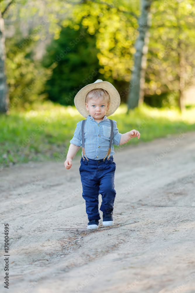 Toddler child outdoors. Rural scene with one year old baby boy with straw hat Toddler child outdoors. Rural scene with one year old baby boy with straw hat