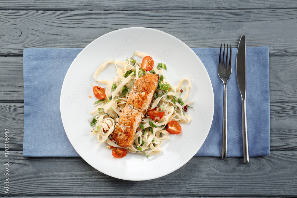 Plate with tasty salmon and pasta on wooden table Plate with tasty salmon and pasta on wooden table