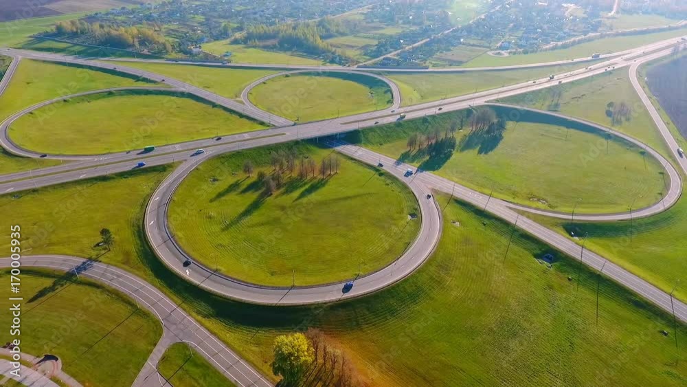 Cars moving on road interchange. Cars traffic on highway intersection. Winding road aerial. Aerial view highway junction. Highway crossing. Aerial view circle road