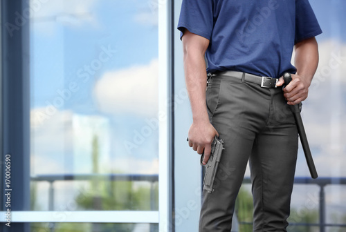 Male security guard with gun near big modern building