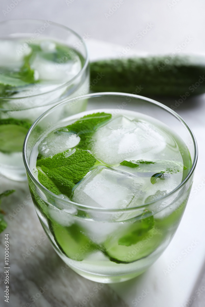 Delicious refreshing water with mint and cucumber in glass on table Delicious refreshing water with mint and cucumber in glass on table