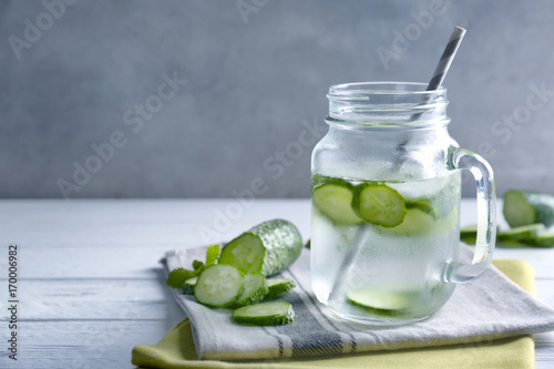 Delicious refreshing water with mint and cucumber in mason jar on table