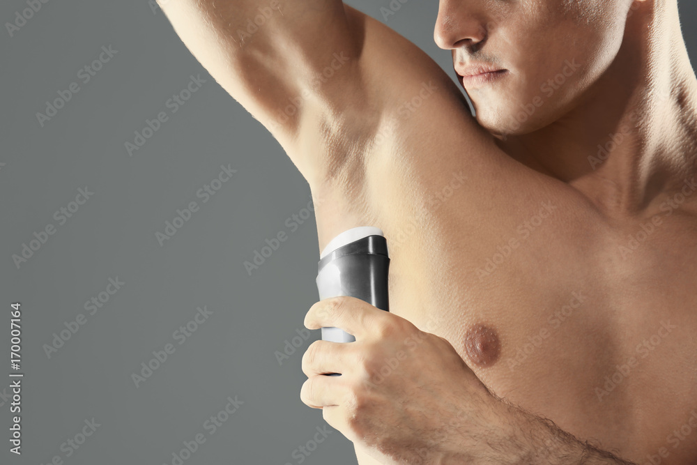 Handsome young man with deodorant on grey background Handsome young man with deodorant on grey background