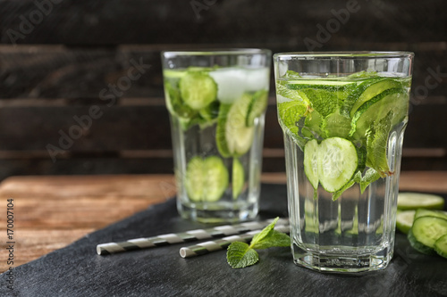 Delicious refreshing water with mint and cucumber in glasses on table